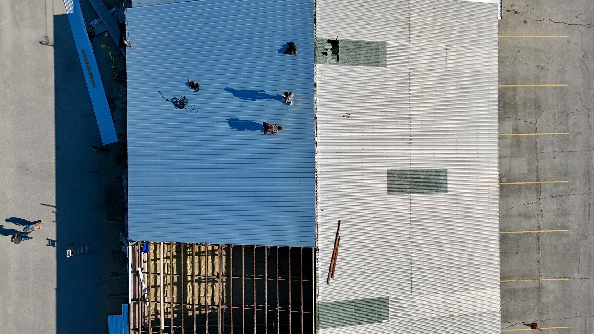 An aerial view of a building under construction with workers on the roof.