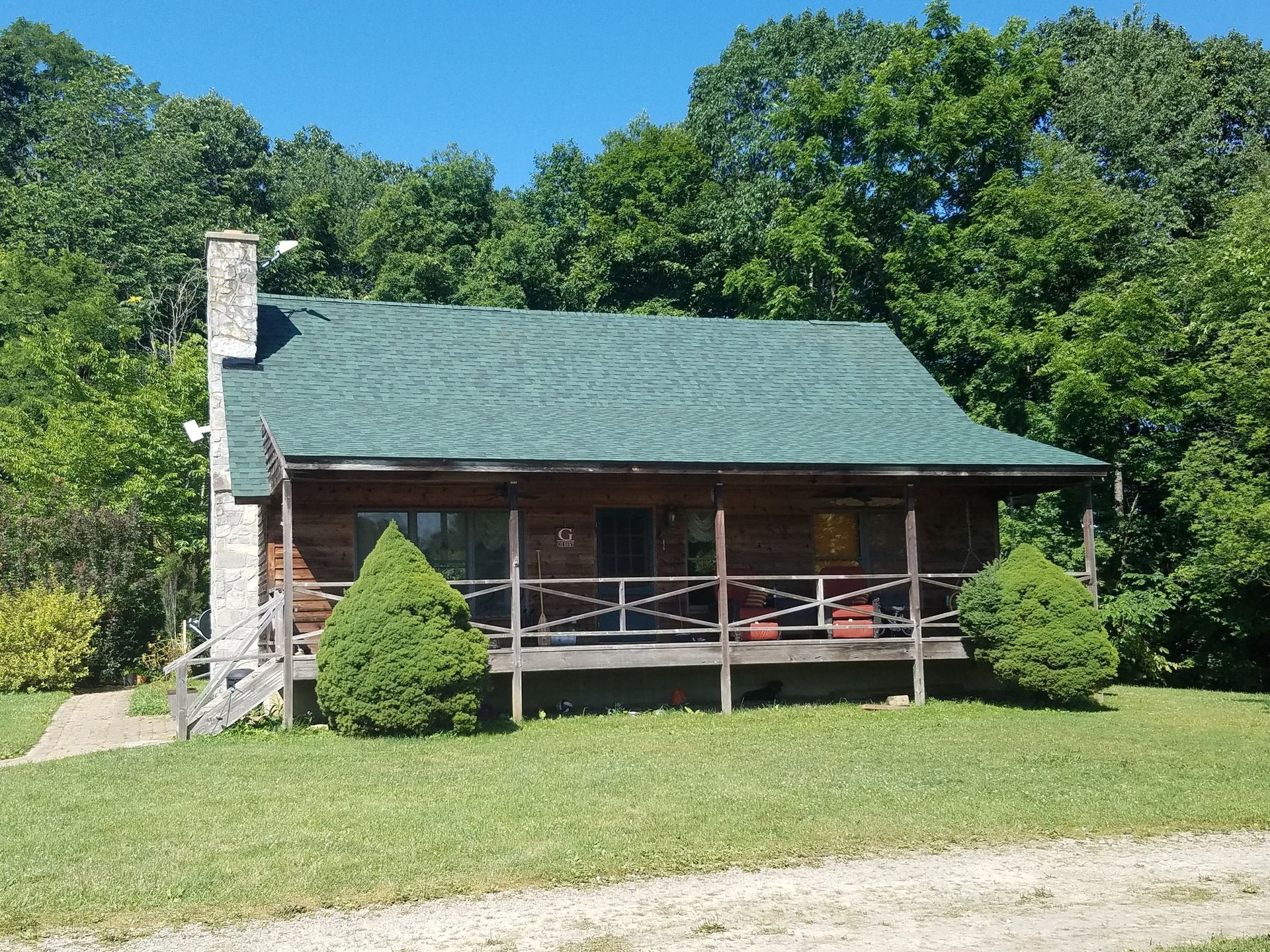A log cabin with a green roof and a porch