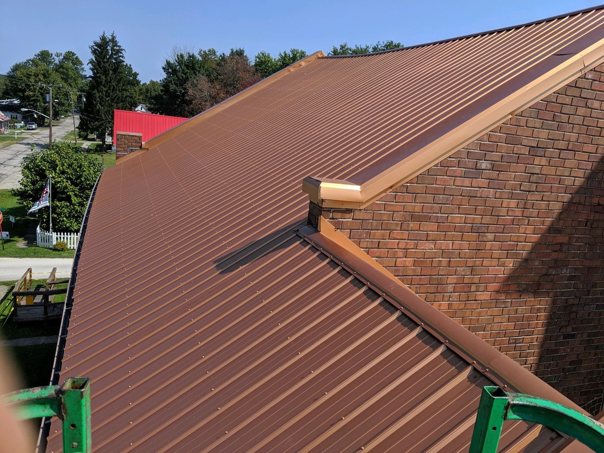 A brown metal roof is being installed on a brick building.