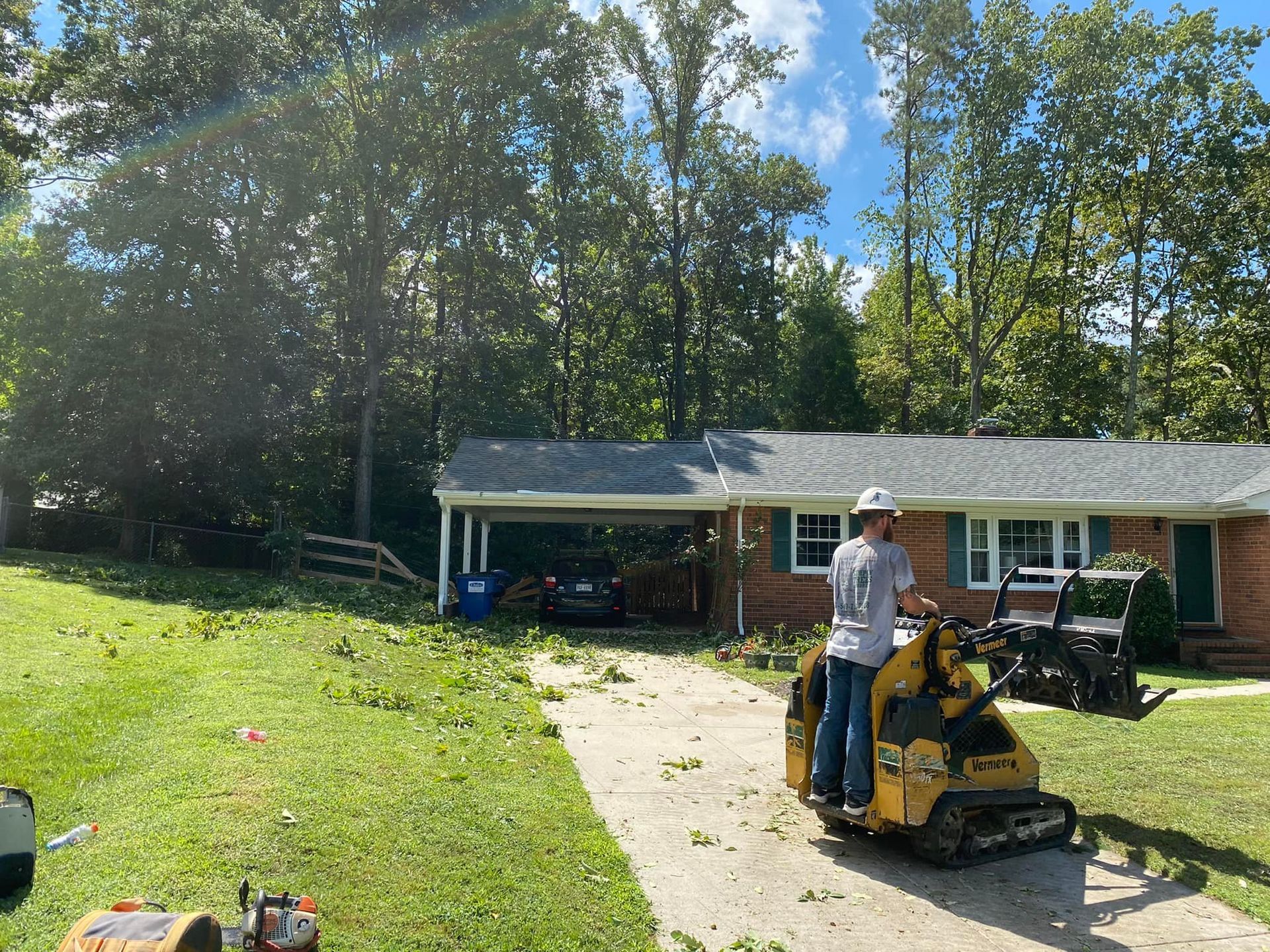 A man is riding a tractor in front of a house.