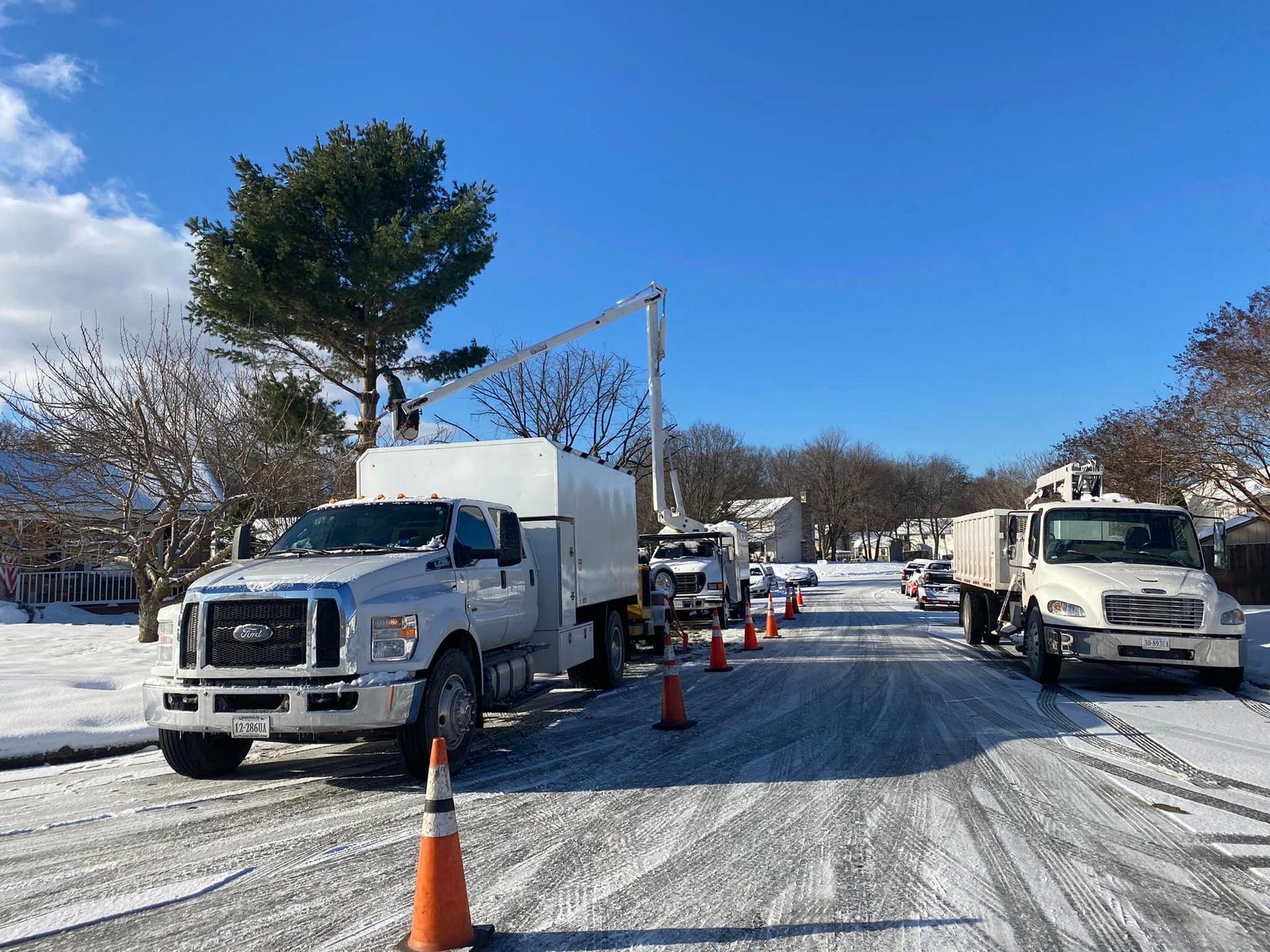 A couple of trucks are parked on the side of the road in the snow.