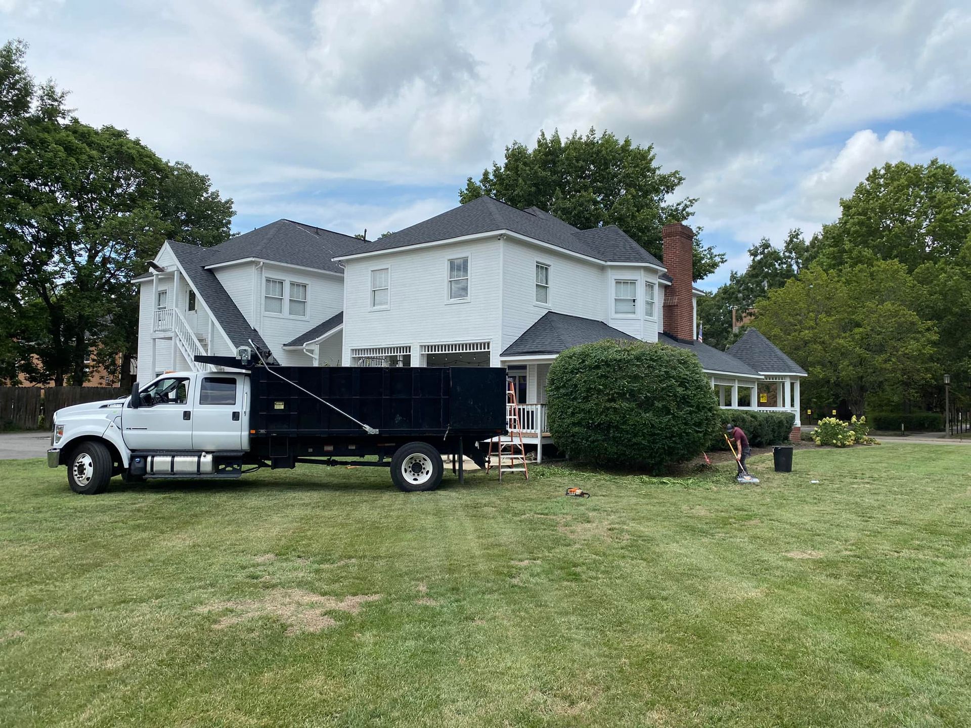 A dump truck is parked in front of a large white house.