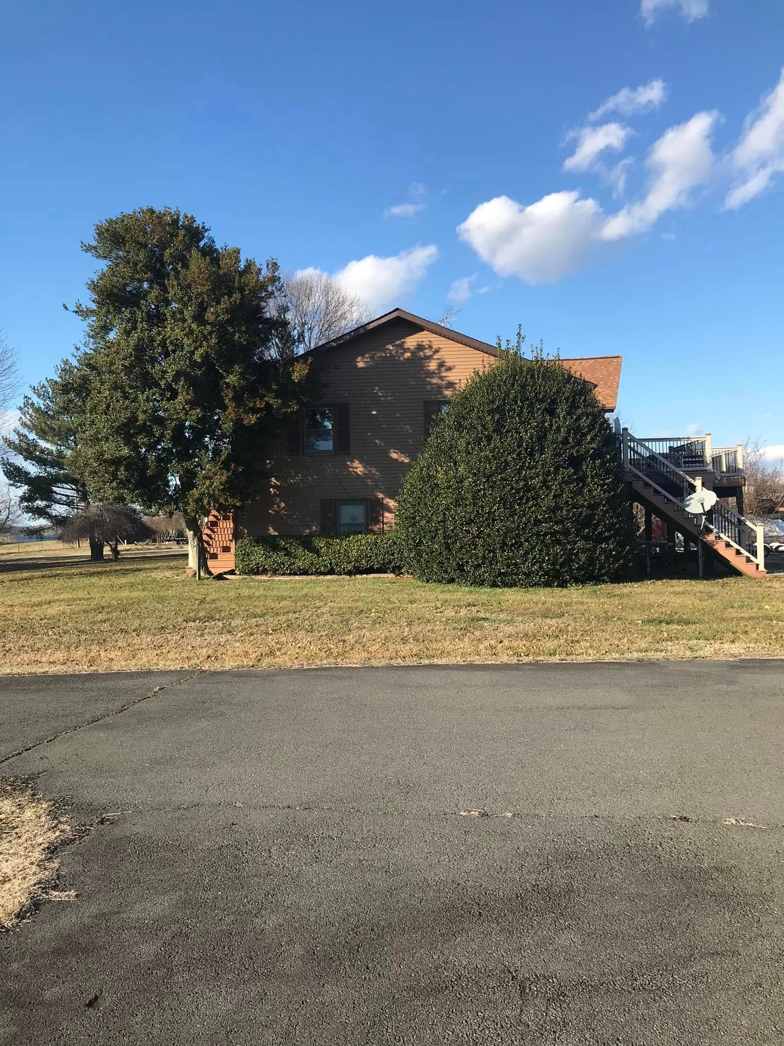 A large brick house with stairs leading up to it is sitting on top of a lush green field.