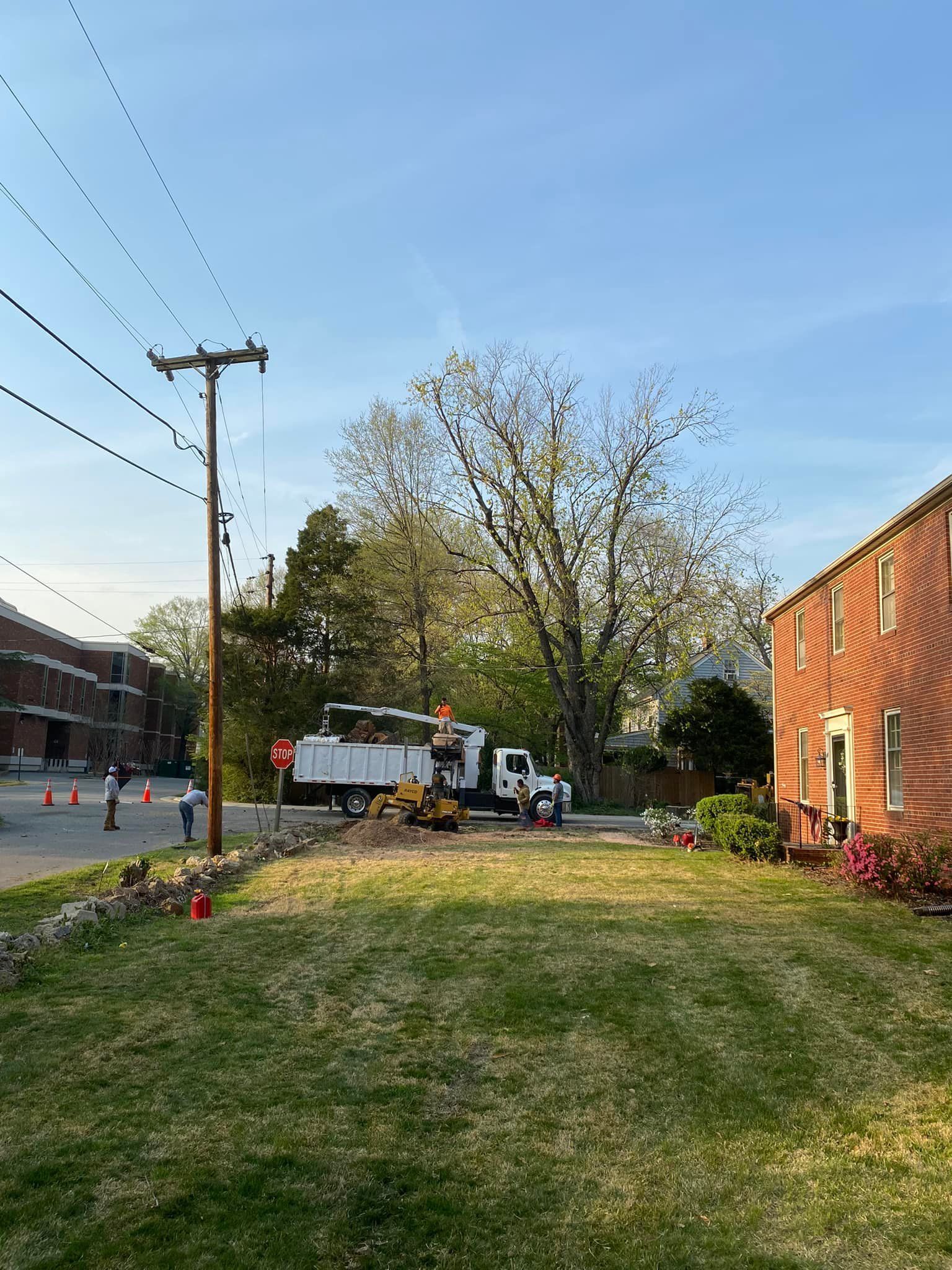 A white truck is parked in a grassy yard next to a brick building.