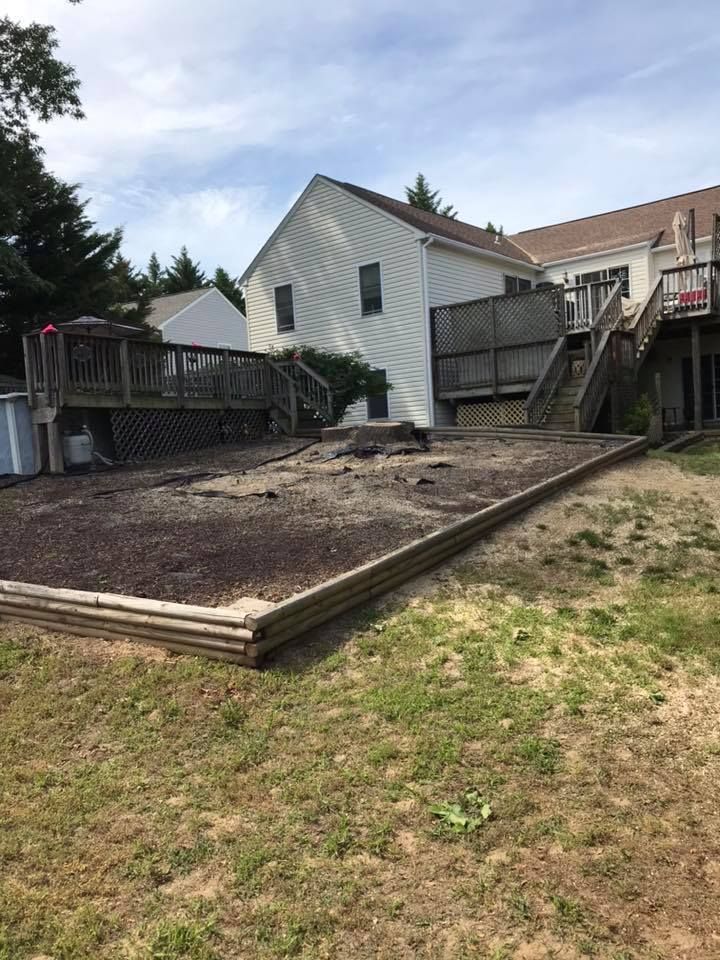 The backyard of a house with a wooden deck and stairs.