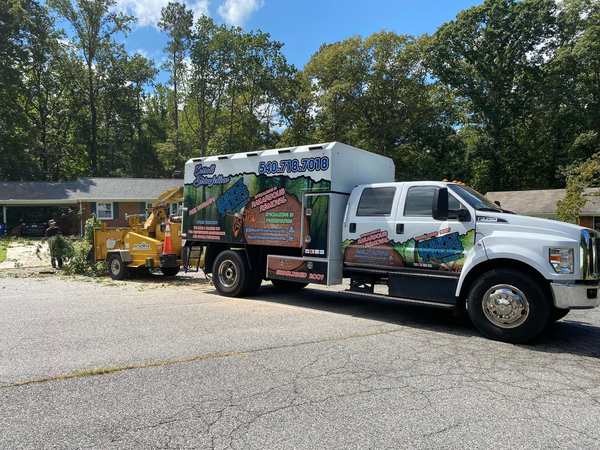 A white truck with a trailer attached to it is parked in front of a house.