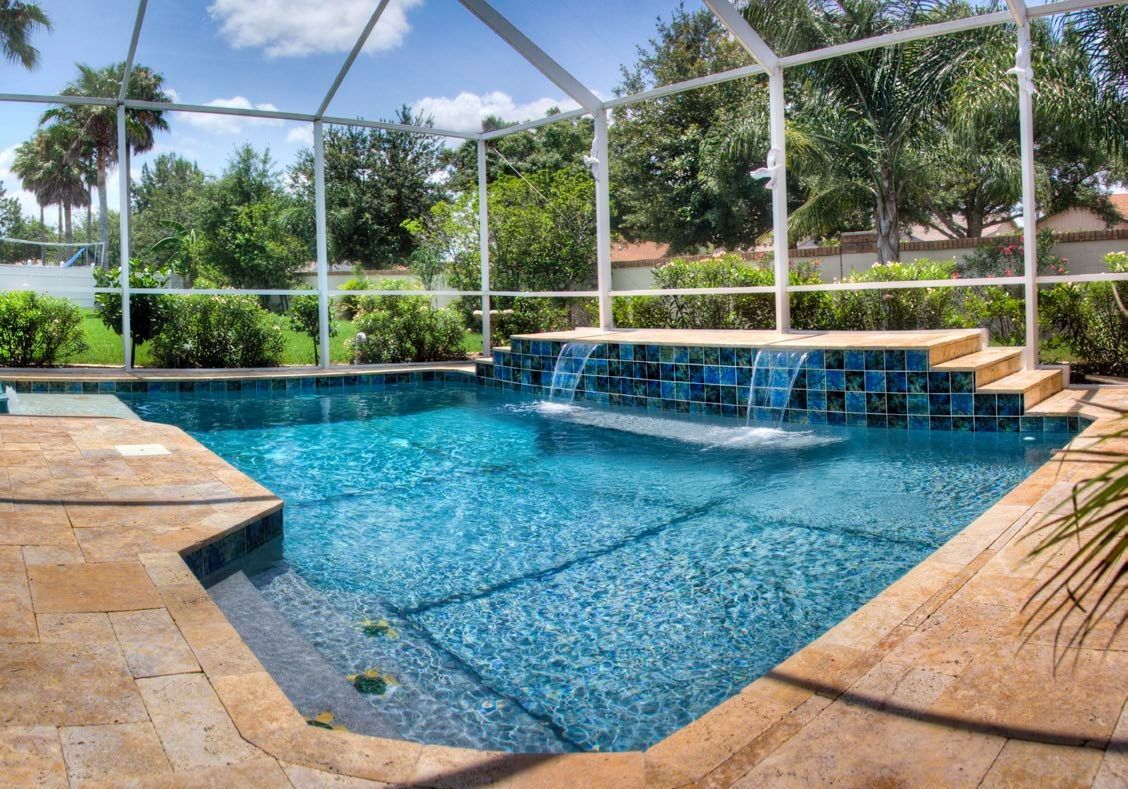 Screened backyard pool with blue water and a rock waterfall under a sunny patio enclosure
