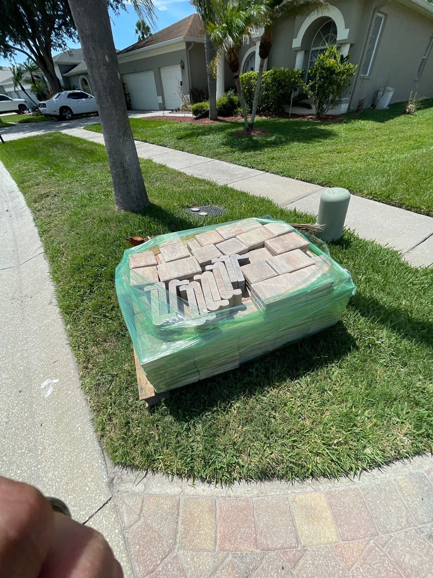Plastic-wrapped box on a grassy lawn beside a sidewalk in front of a house.