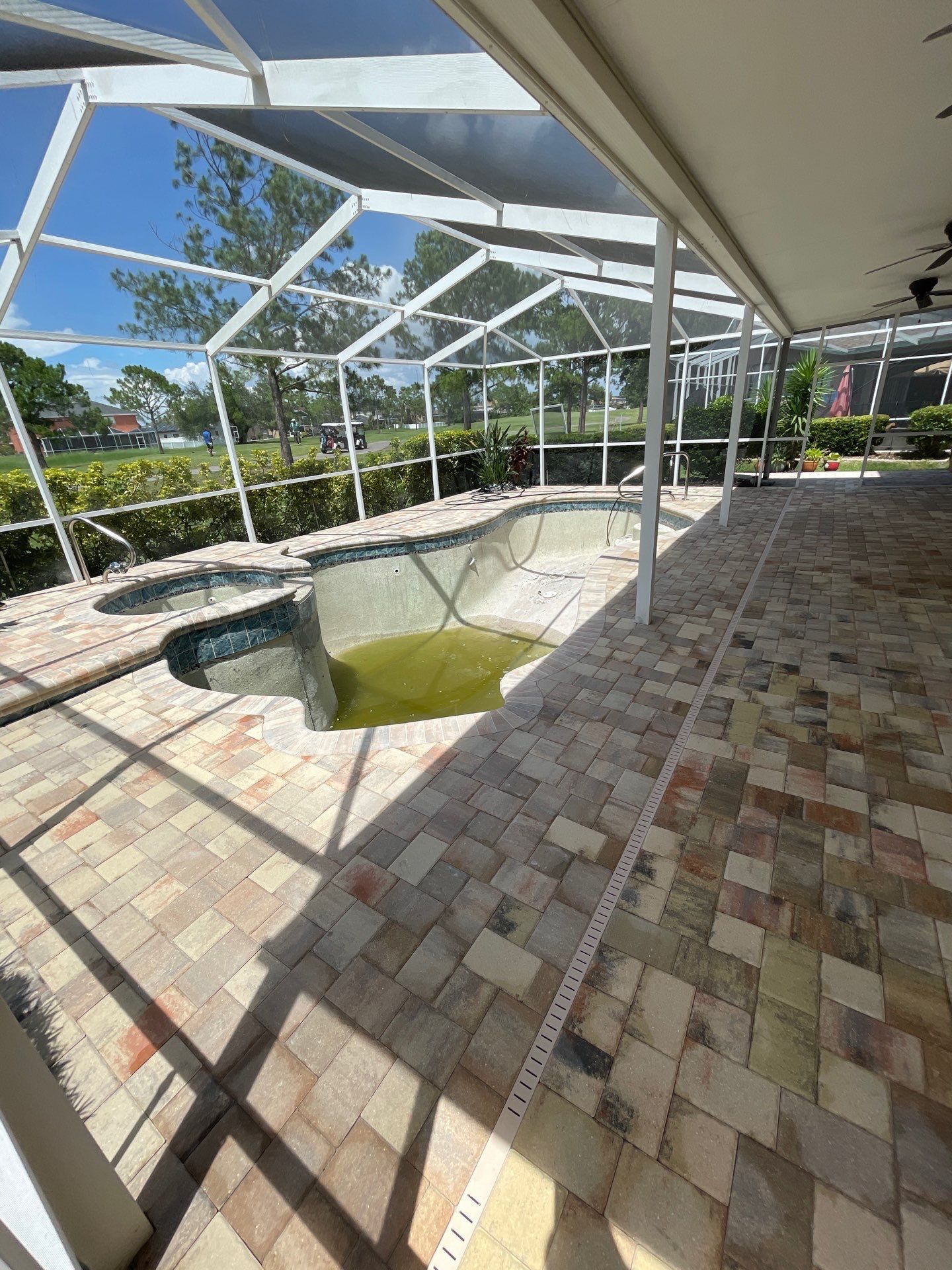 Screened patio with a small empty pool and tiled floor in bright sunlight.