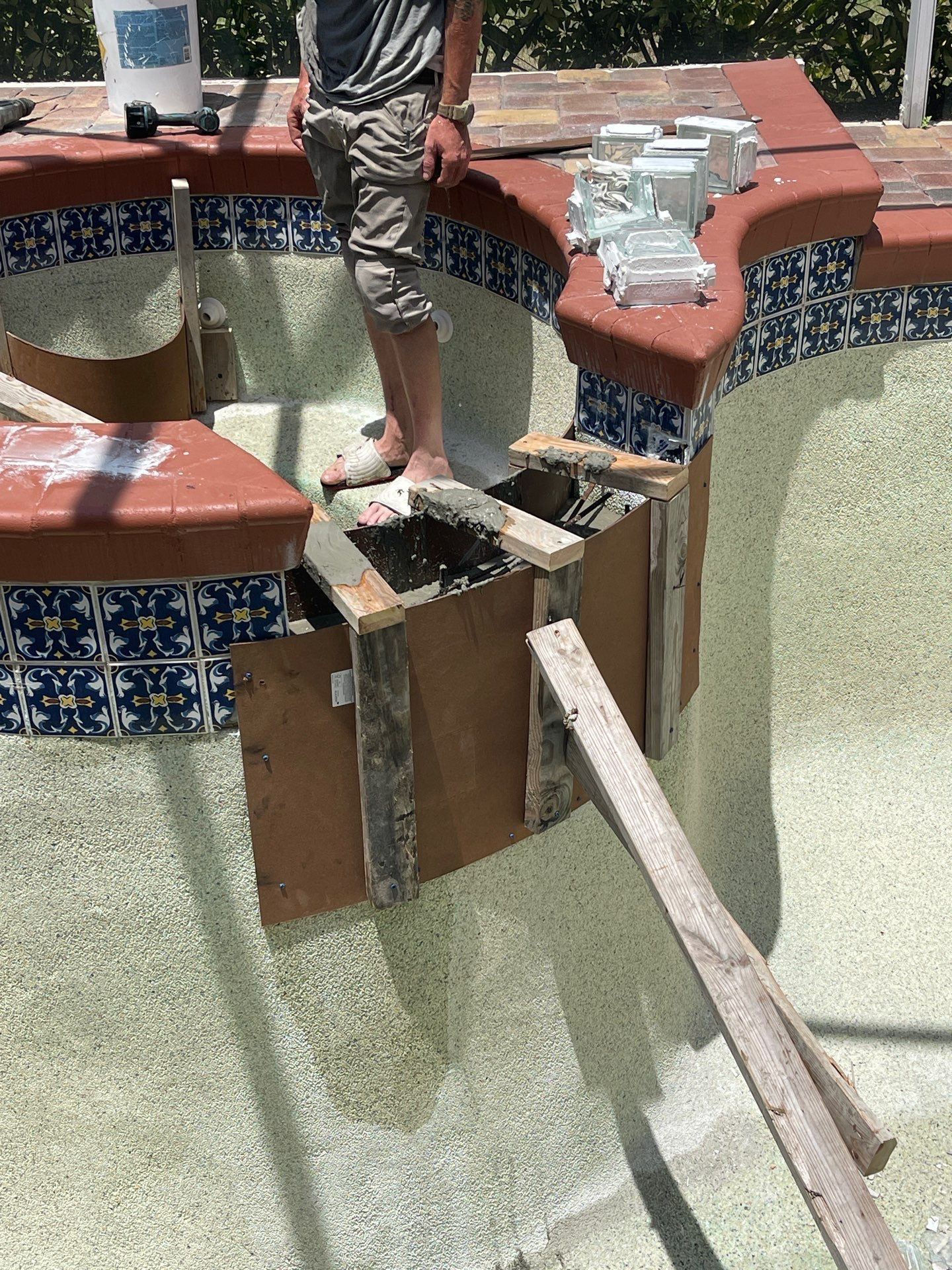Broken swimming pool with a person standing on the damaged edge and exposed wood support underneath.