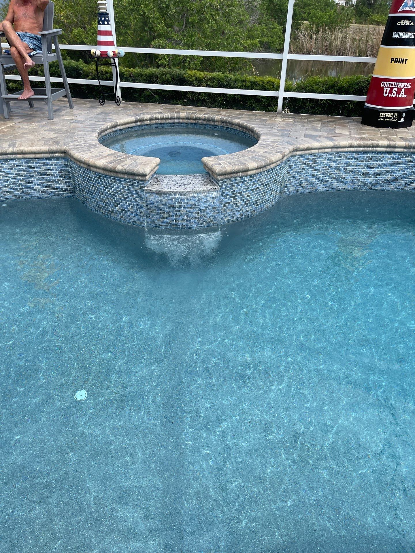 Backyard pool with a circular hot tub and white railings.
