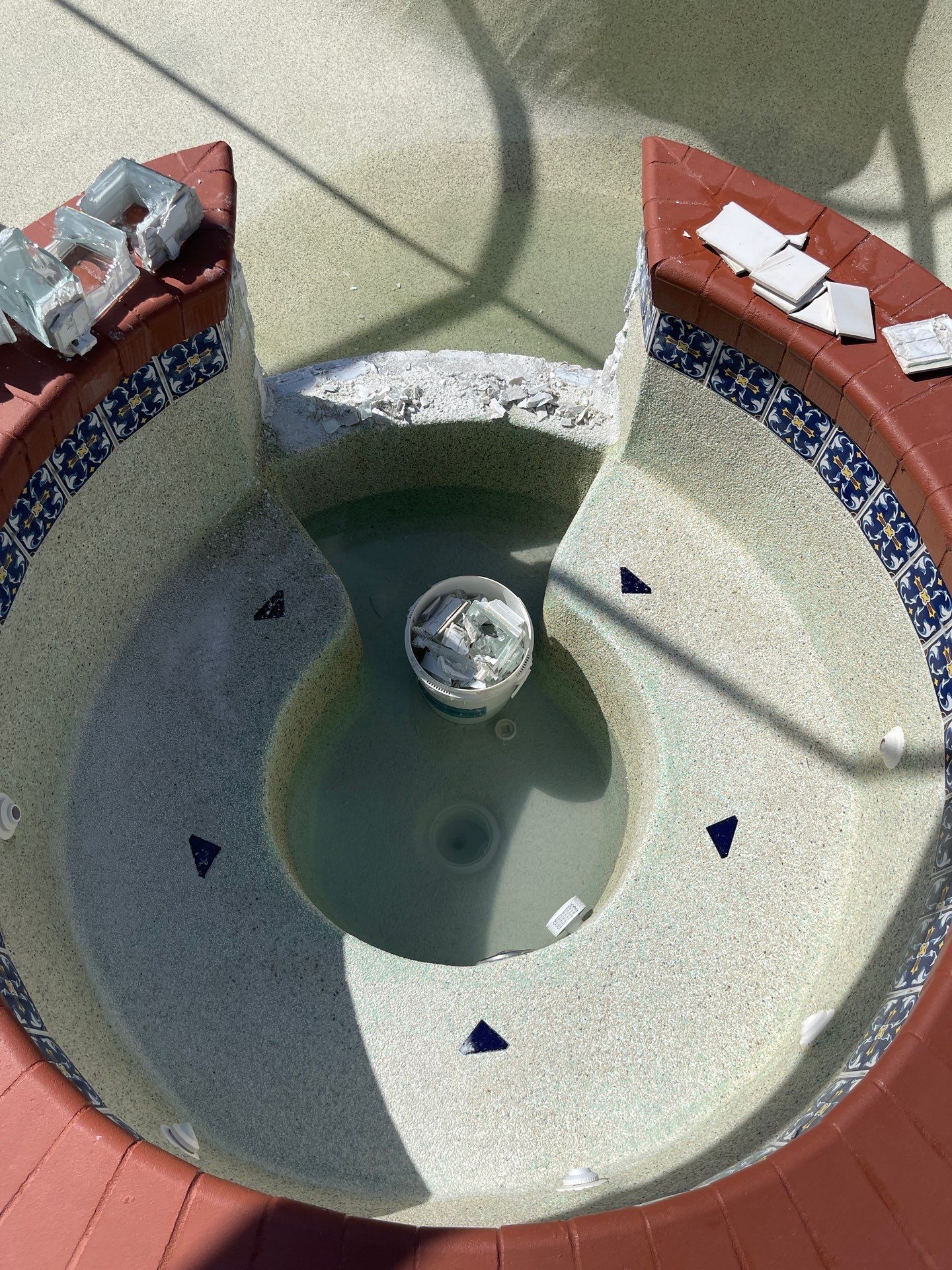 Round fountain with shallow water, tiled basin, and a small central spout in a courtyard.