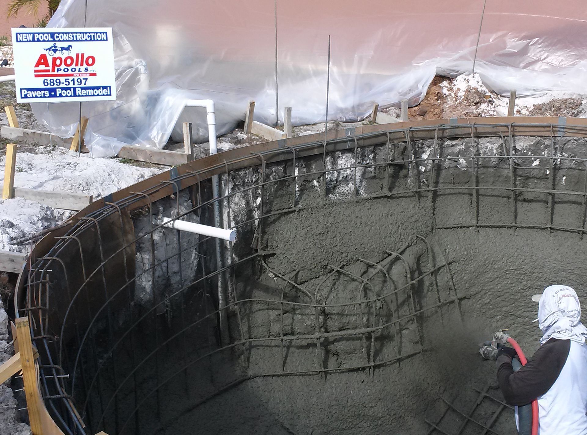 Worker spraying concrete inside a large circular tank under construction