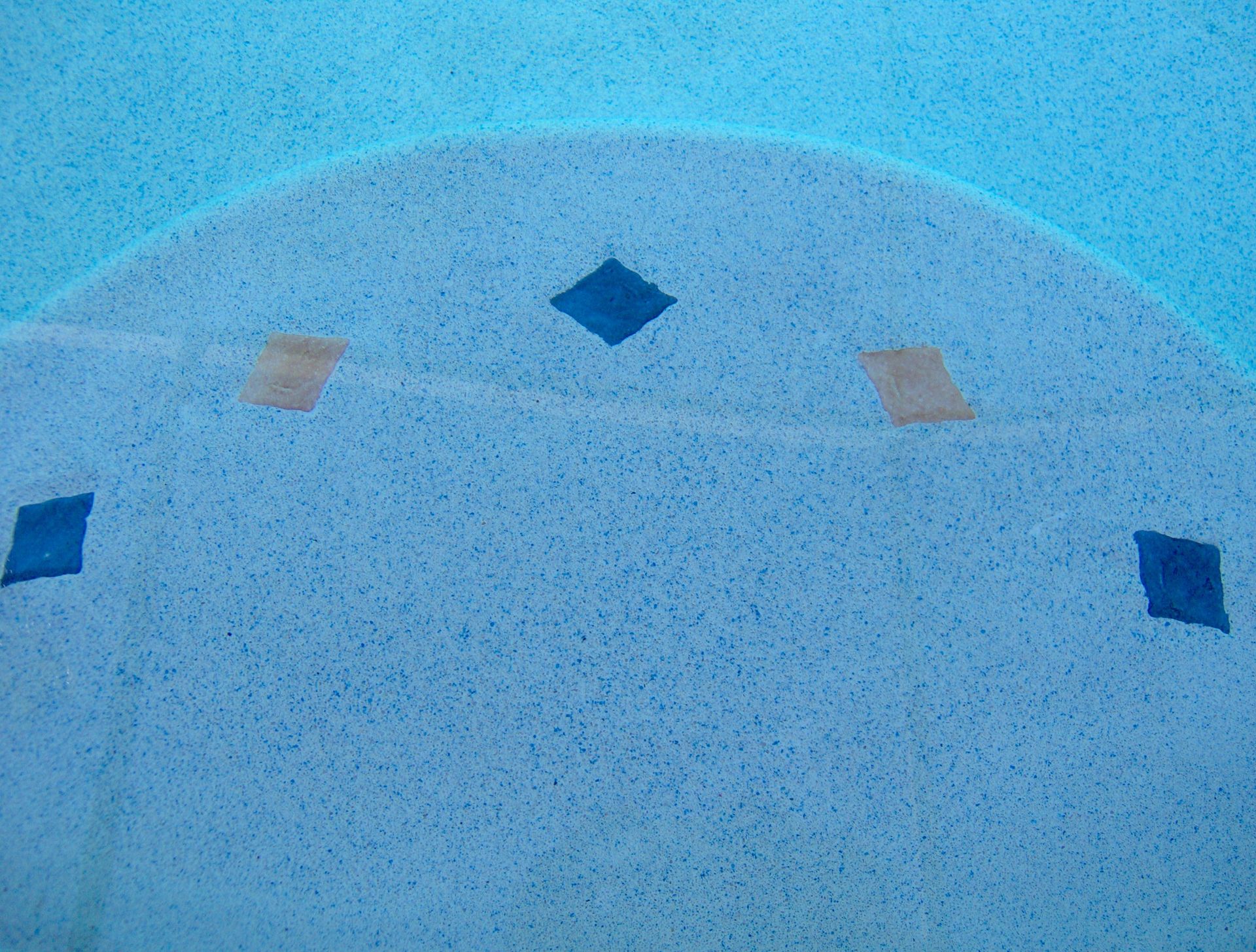 Blue tiled pool wall with a curved edge and small diamond accents