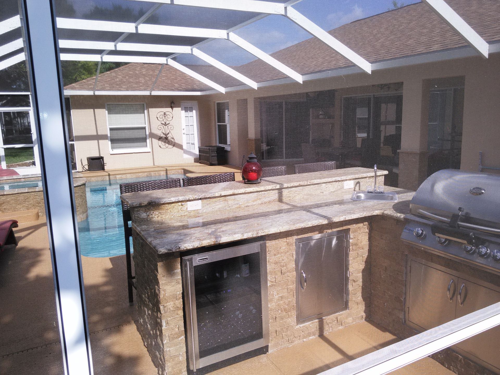 Outdoor patio kitchen with built-in grill, sink, and covered seating area under a pergola.
