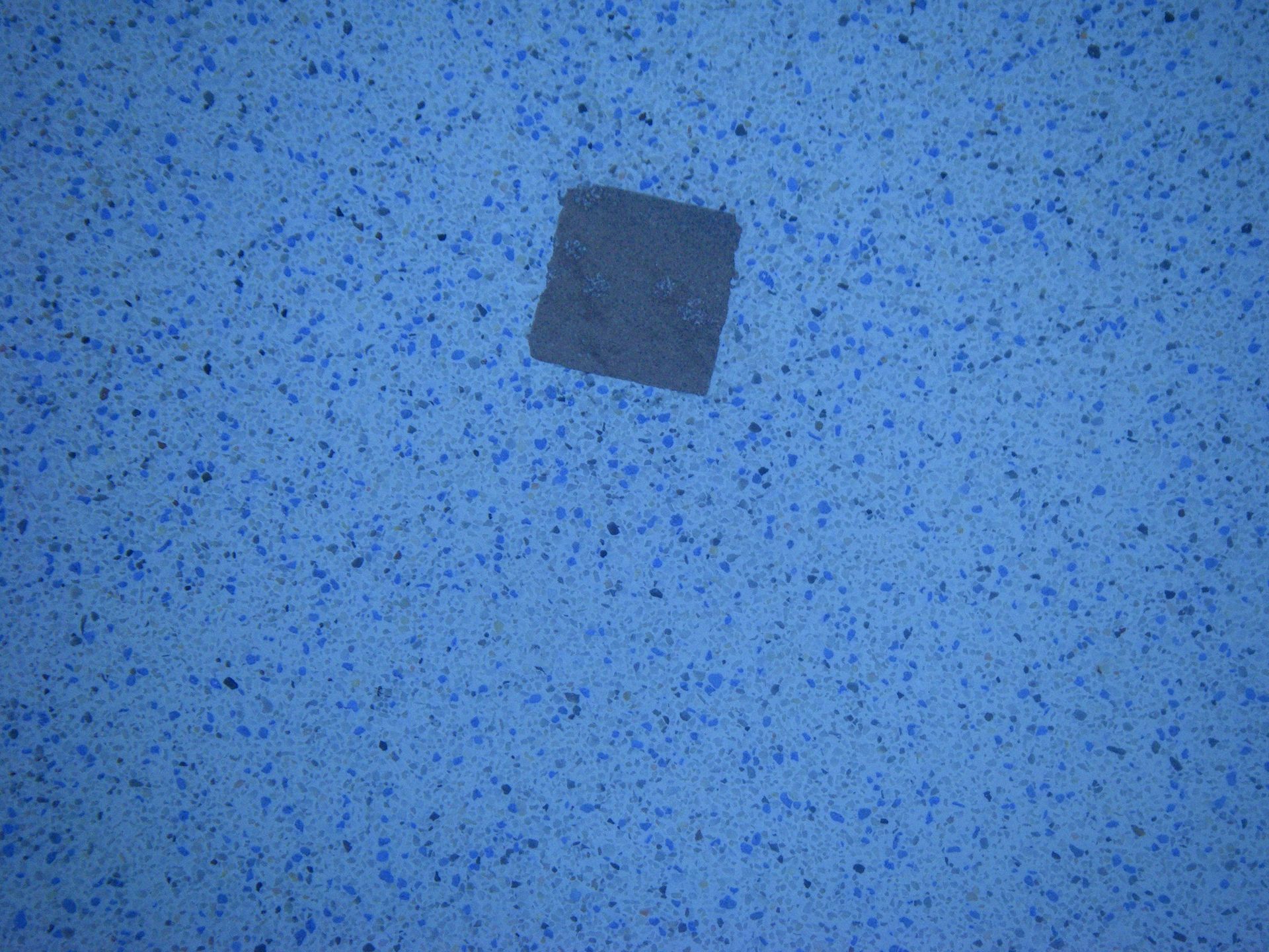 Blue speckled surface with a small dark square near the center