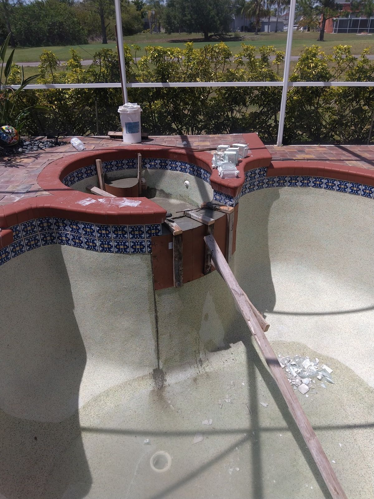 Outdoor tiled fountain basin with a red circular top and central water feature, viewed from above.