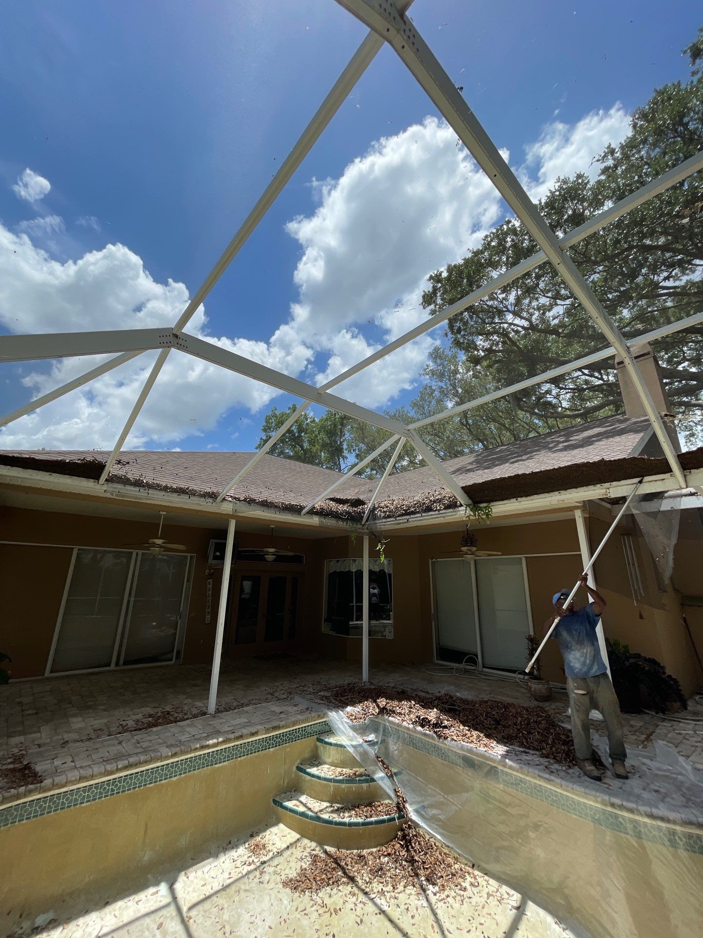 Damaged courtyard roof with exposed beams; a person stands near a central fountain under blue sky.