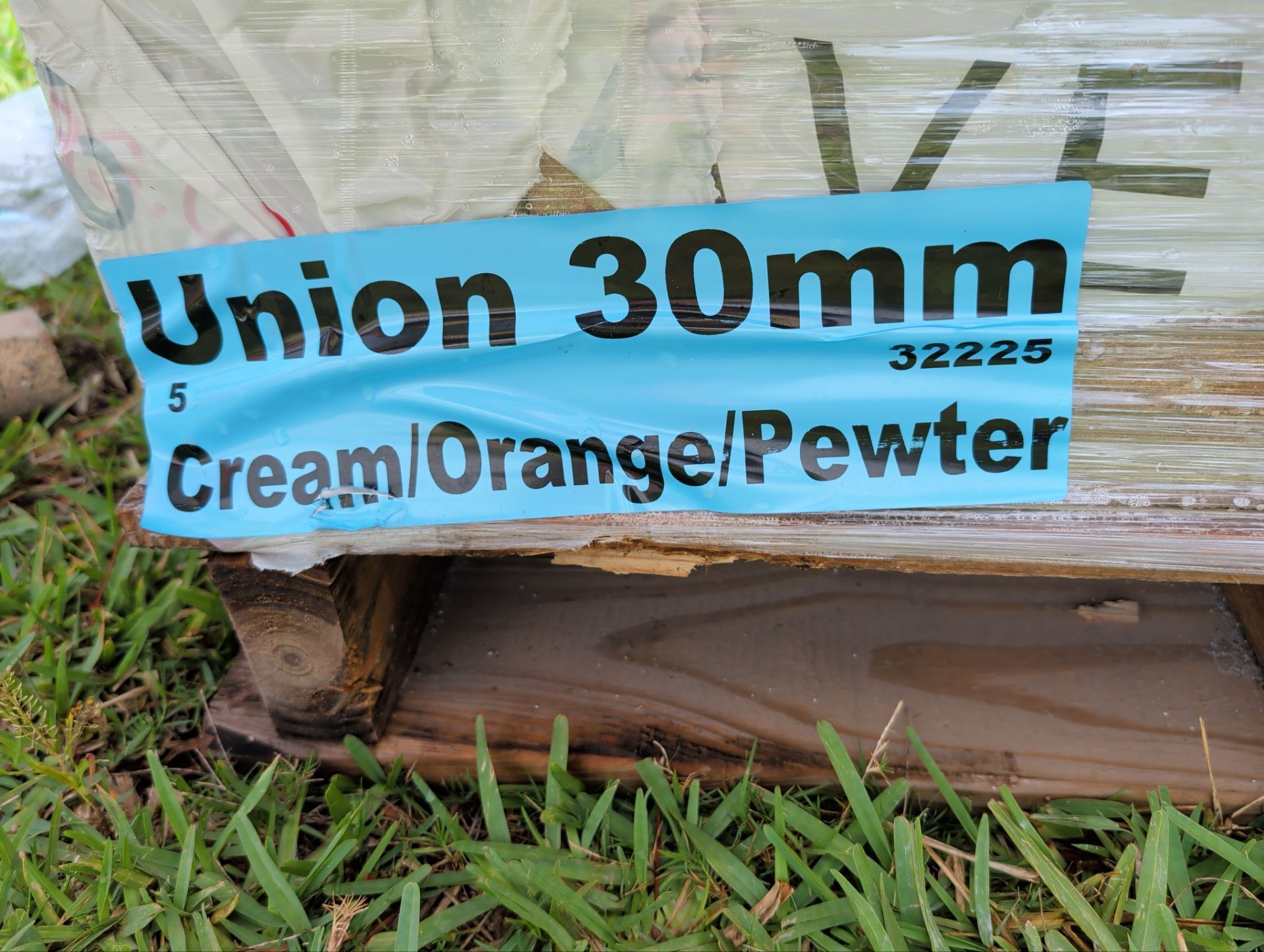 Blue label on a wrapped pallet reading “Union 30mm” and “Cream/Orange/Pewter” on grass.