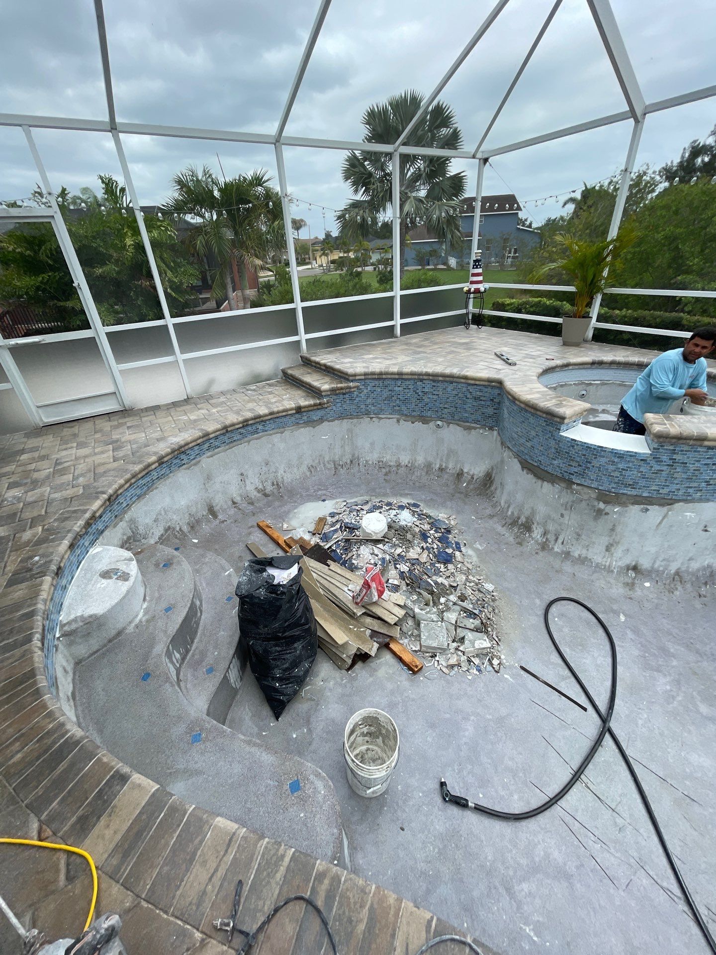 Indoor pool under construction with a worker kneeling near a large circular basin and building materials scattered nearby.