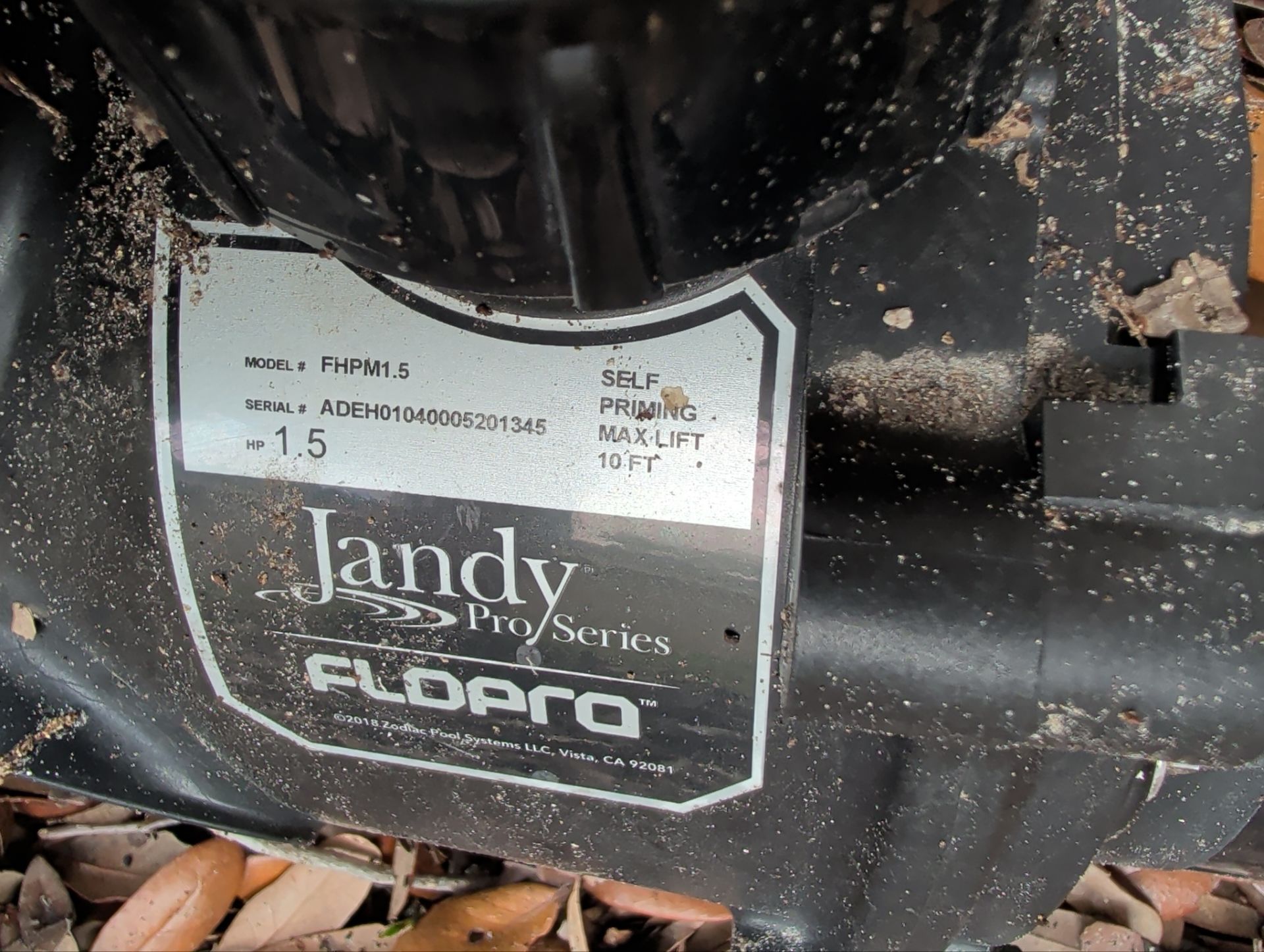 Close-up of a dusty black motor with a white Jandy Pro Series label and a red switch.