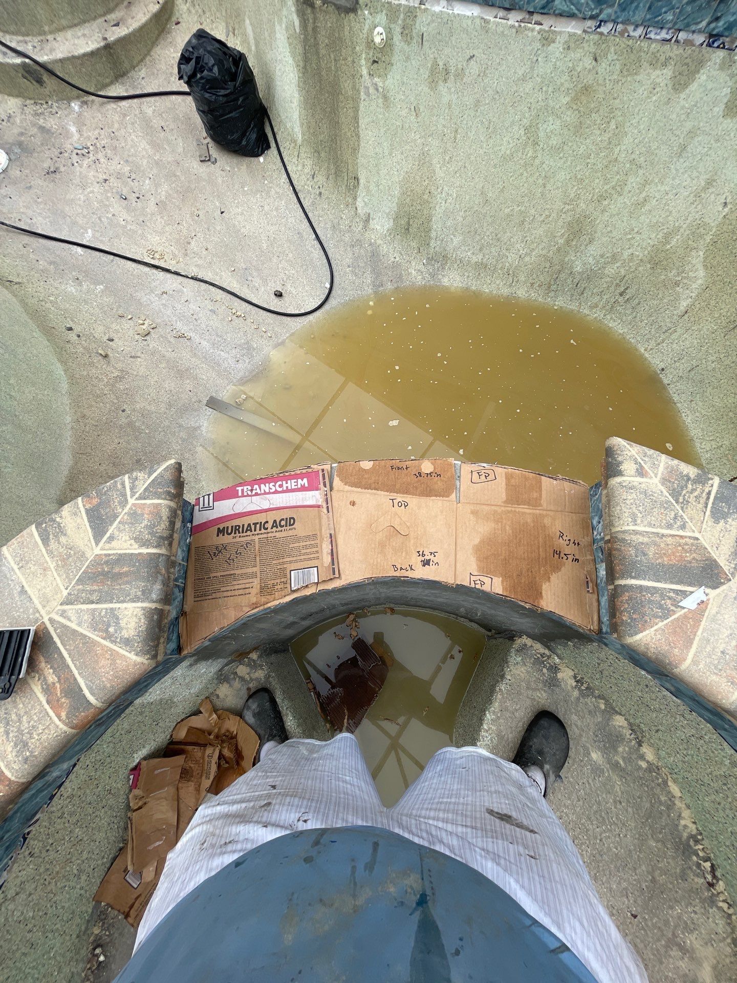 Overlooking a flooded concrete area with muddy water, scattered debris, and a shoe near the wall.