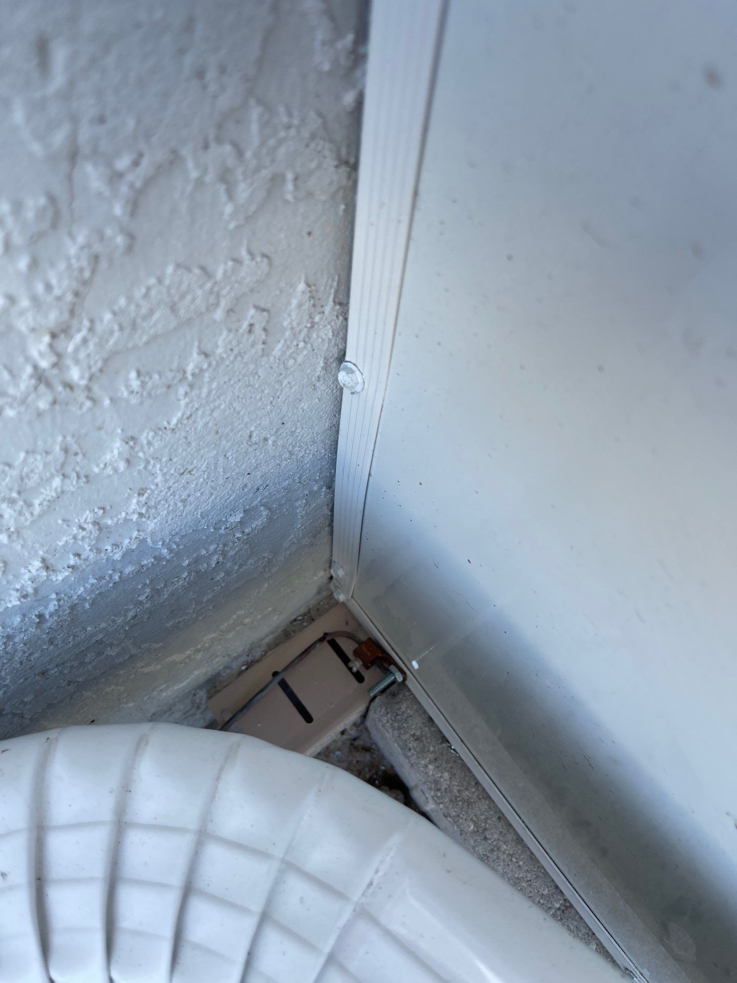 Close-up of a wall corner with peeling paint and a white vent or appliance edge in the foreground.