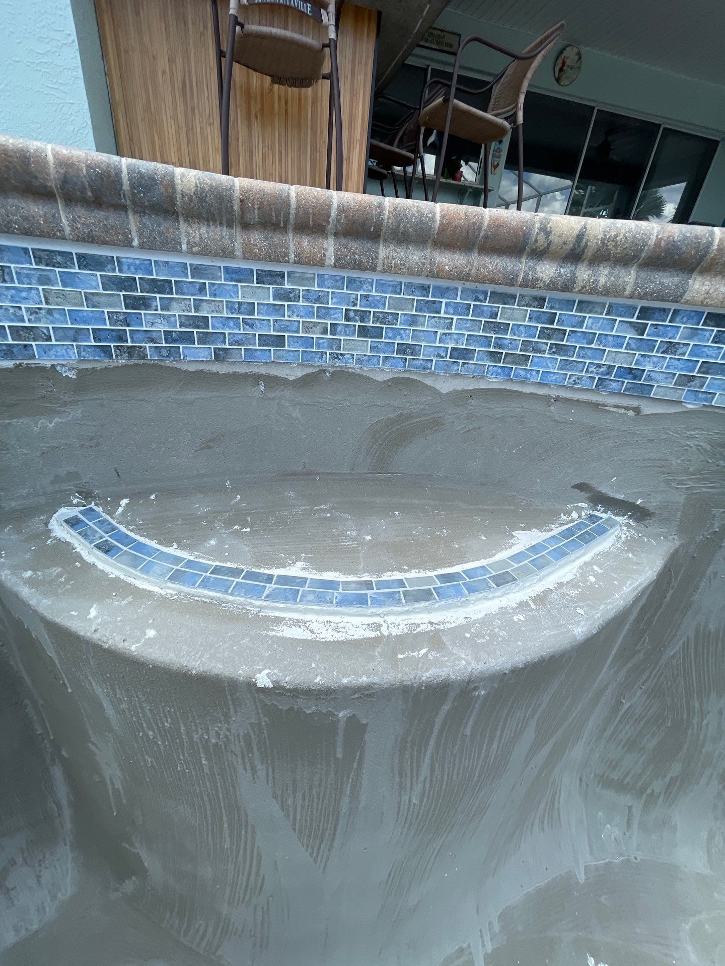 Empty fountain basin with a curved blue-tiled water spout and wet concrete surface.