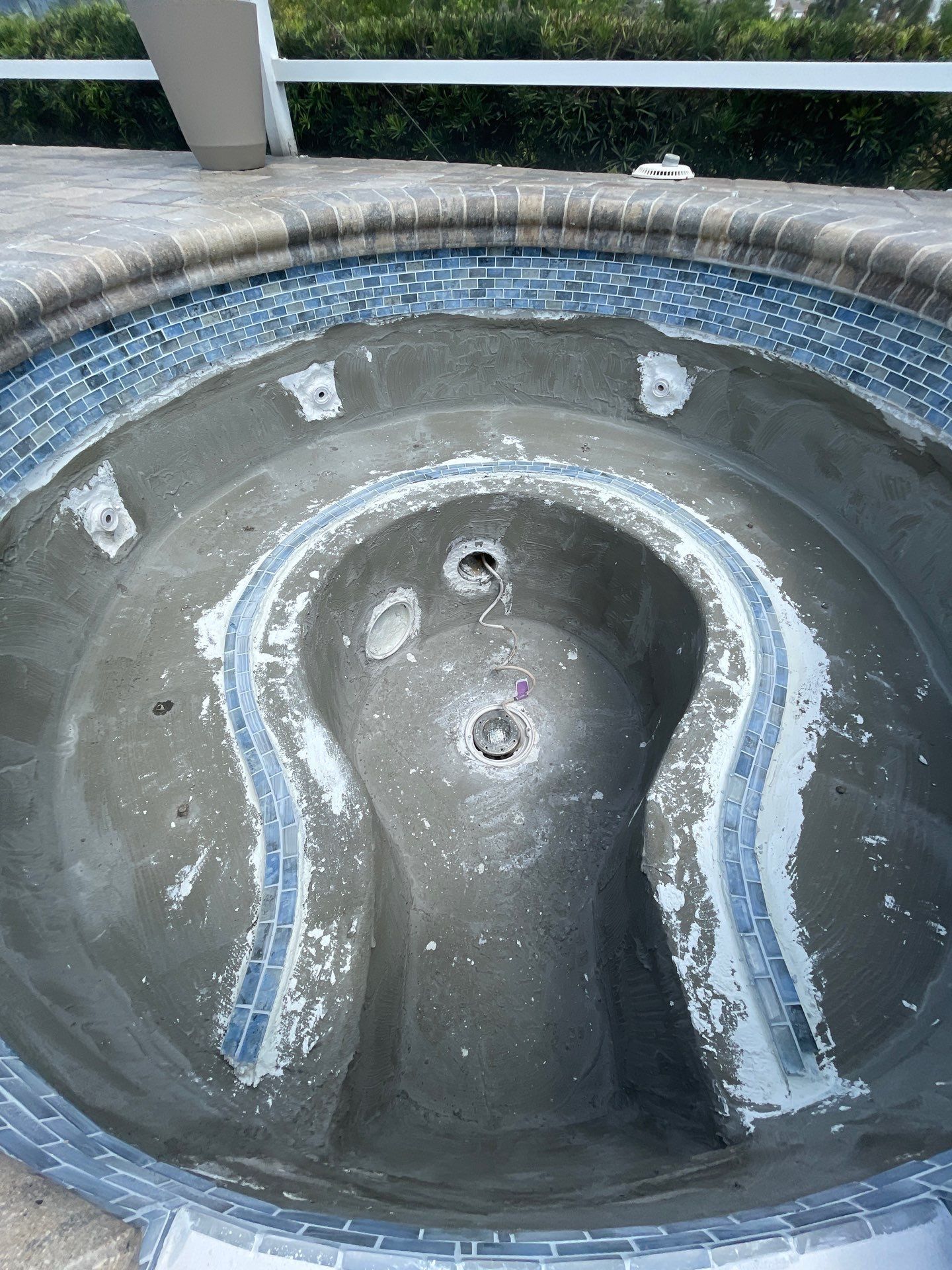 Broken public fountain basin with blue-and-white tile trim and water stains.