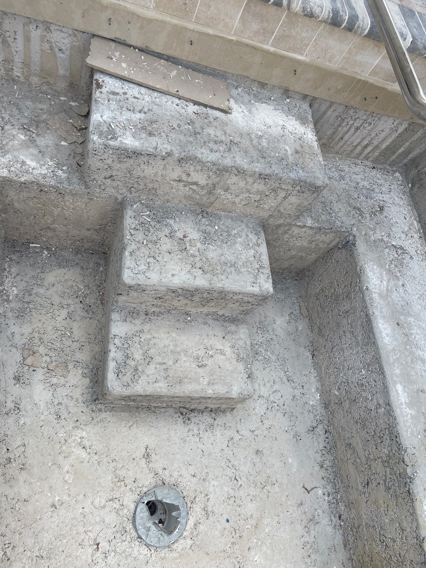 Concrete stairwell with small built-in steps and a drain hole in the floor.