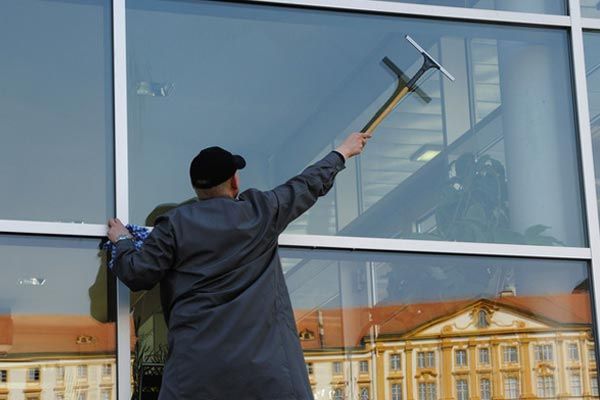 Man cleaning commercial window with squeegee