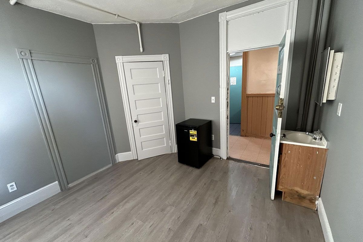 An empty room with hardwood floors , gray walls , and a door.