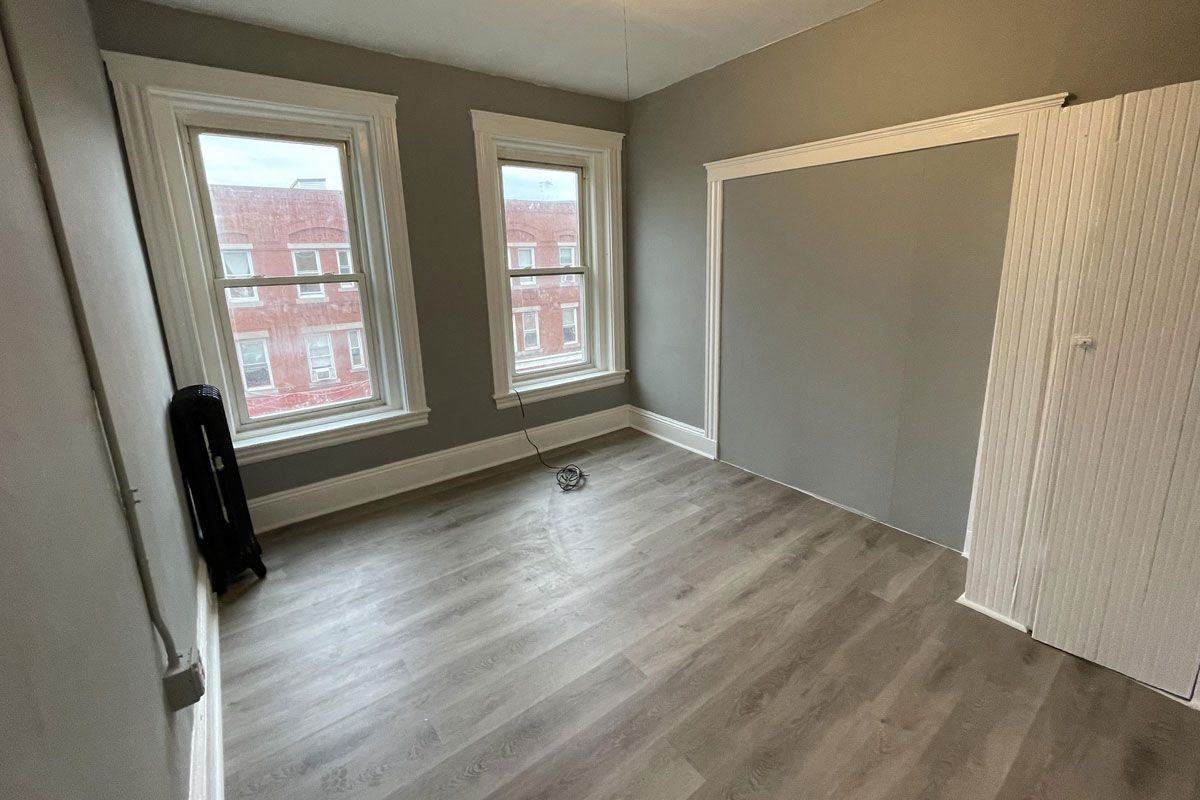 An empty room with hardwood floors and two windows.