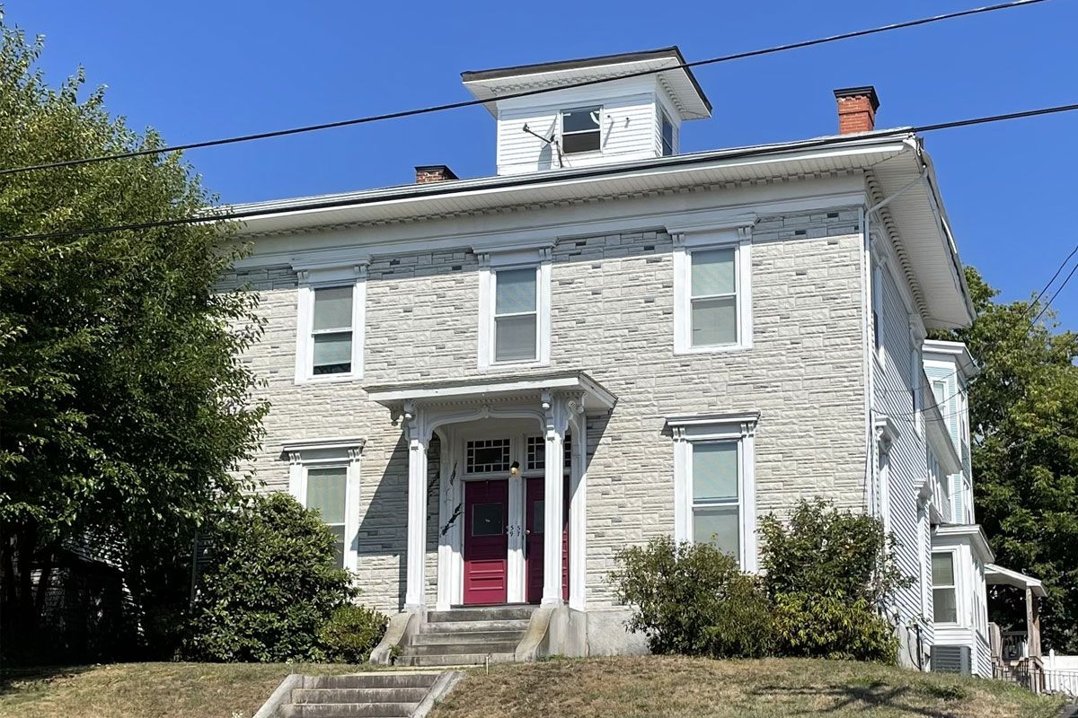 A large white house with a red door and stairs in front of it.