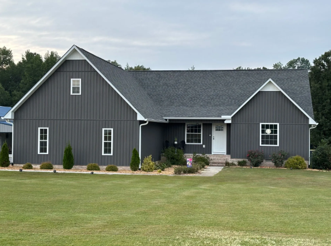 Gray-sided house with white trim, gable roof, and manicured lawn.