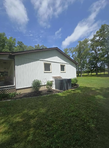 White building with small windows, brown trim, and a grassy yard under a blue sky.