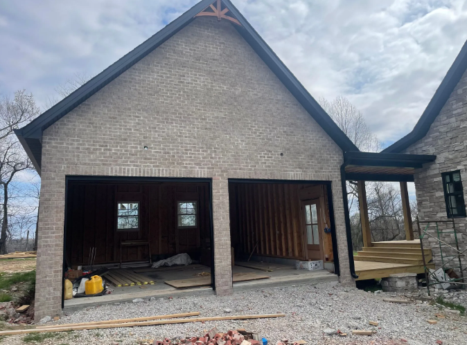 New construction brick garage with wooden interior and porch on a cloudy day.