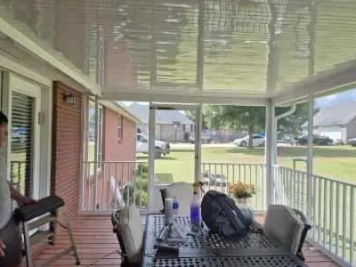 Screened-in porch overlooking a yard; a man is standing nearby; dining table with chairs.