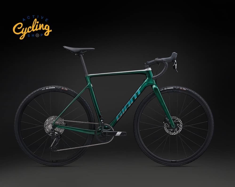 A green bicycle is sitting on a black surface.
