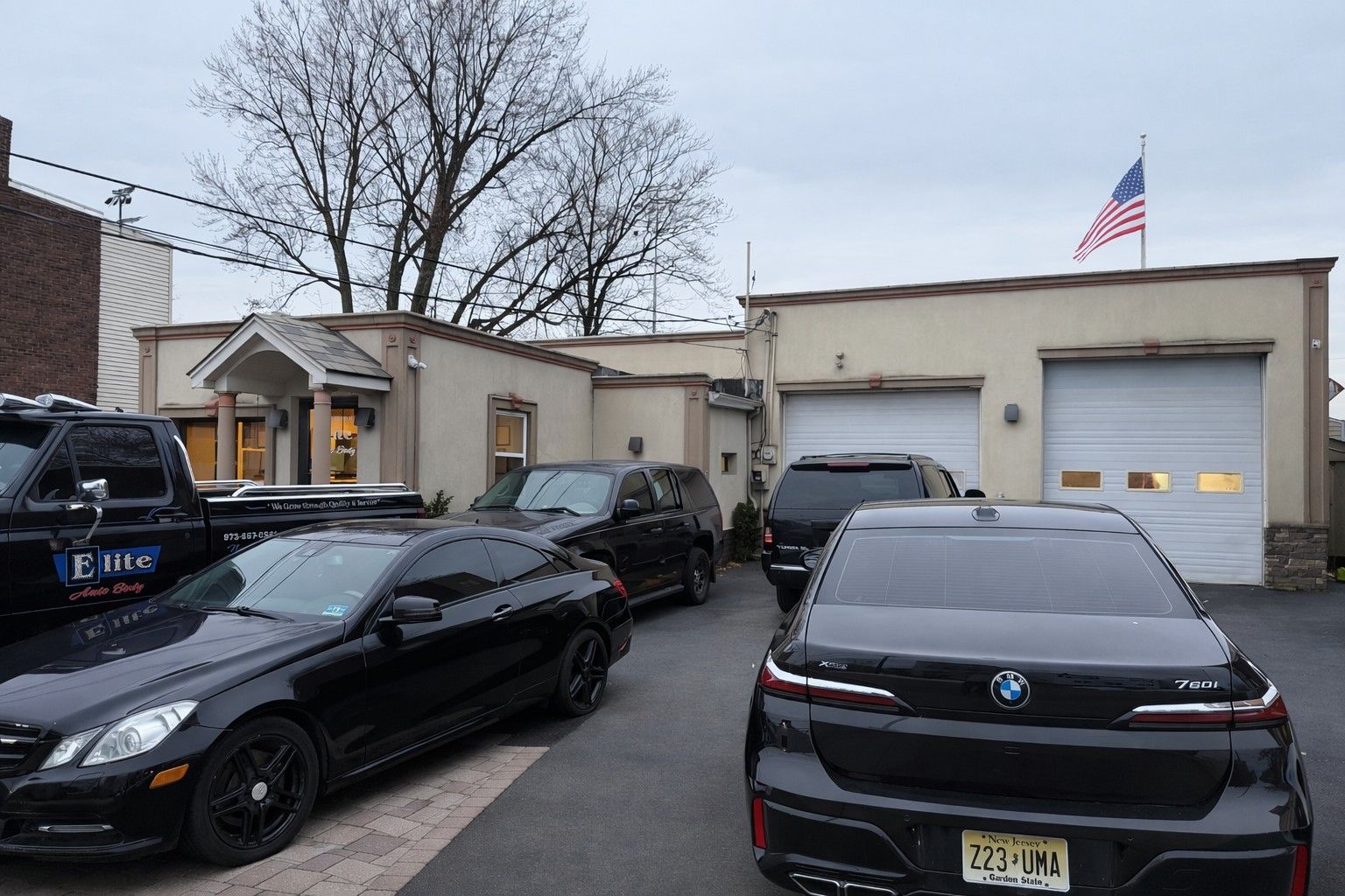 Black cars parked in front of a beige building with a US flag.