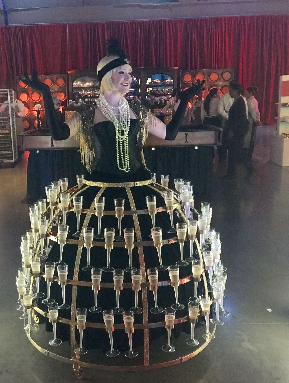 A woman in a dress is holding a glass of champagne