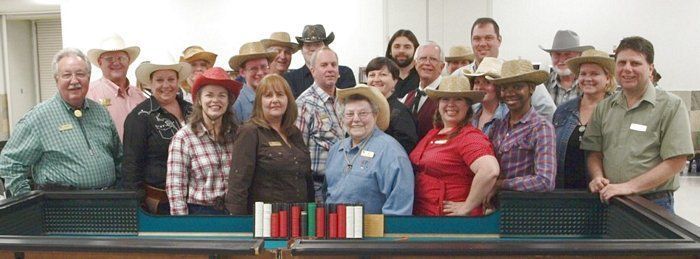 A group of people wearing cowboy hats are posing for a picture