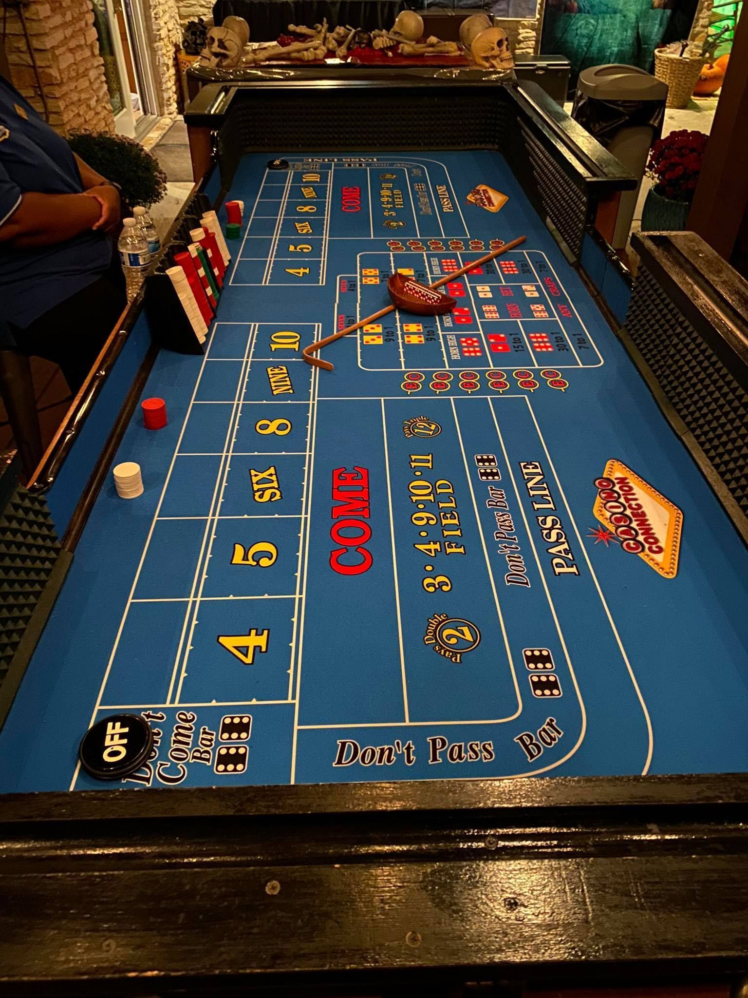 A blue craps table with a man standing behind it