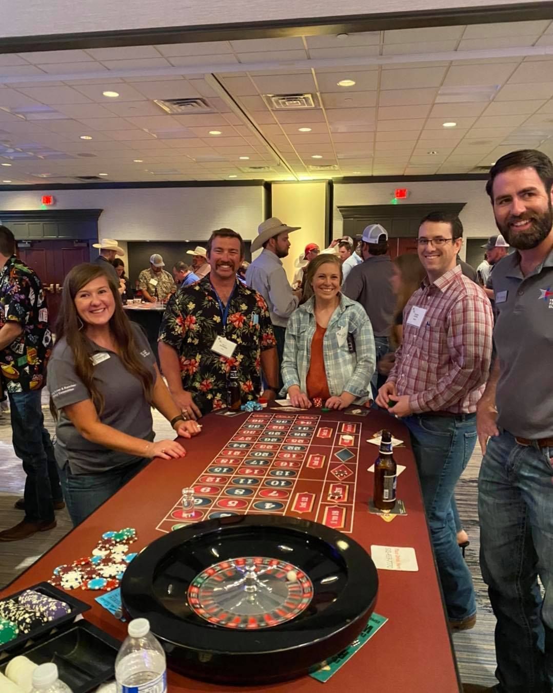 A group of people are standing around a roulette table.