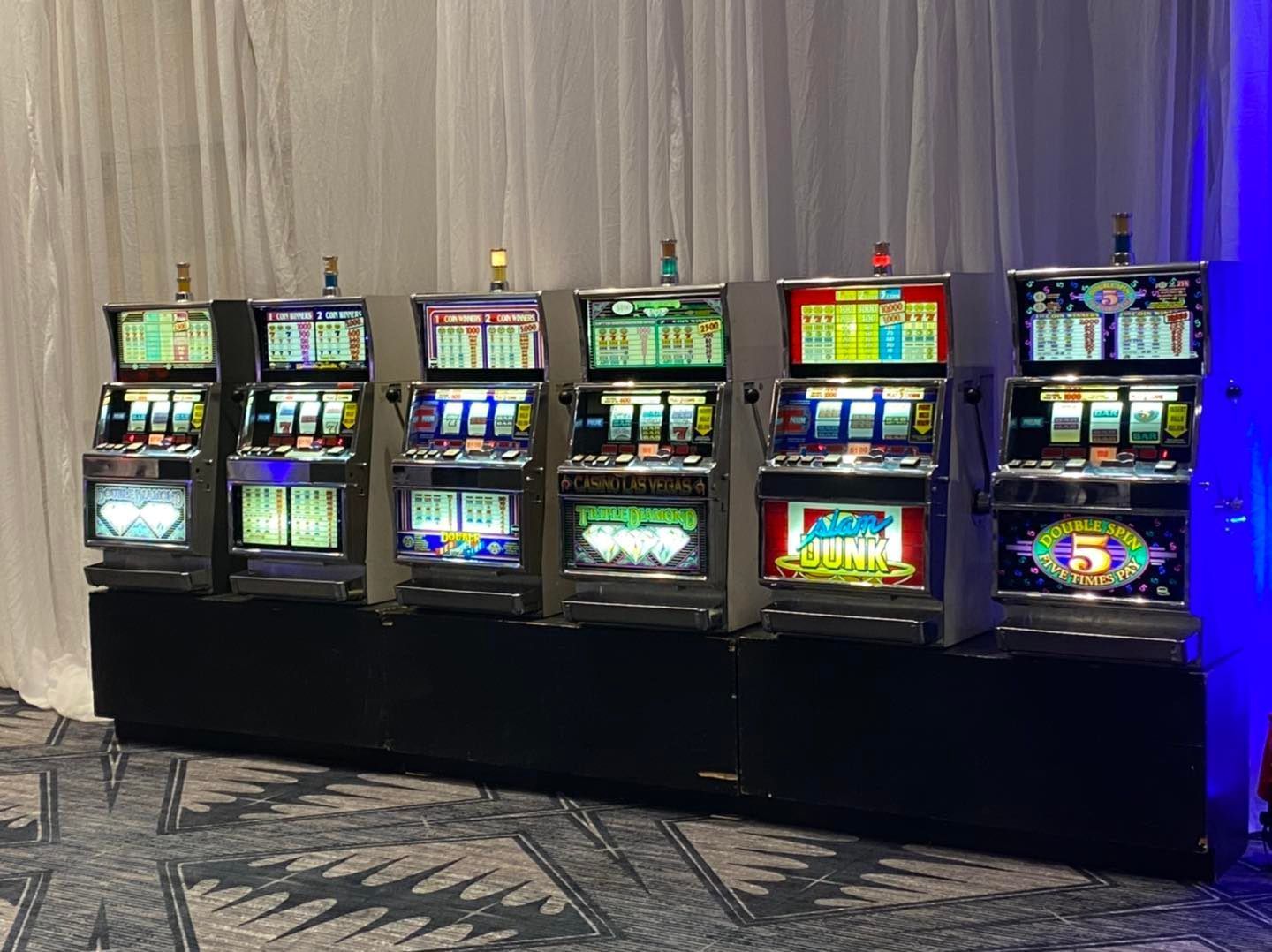 A row of slot machines are lined up in a room.