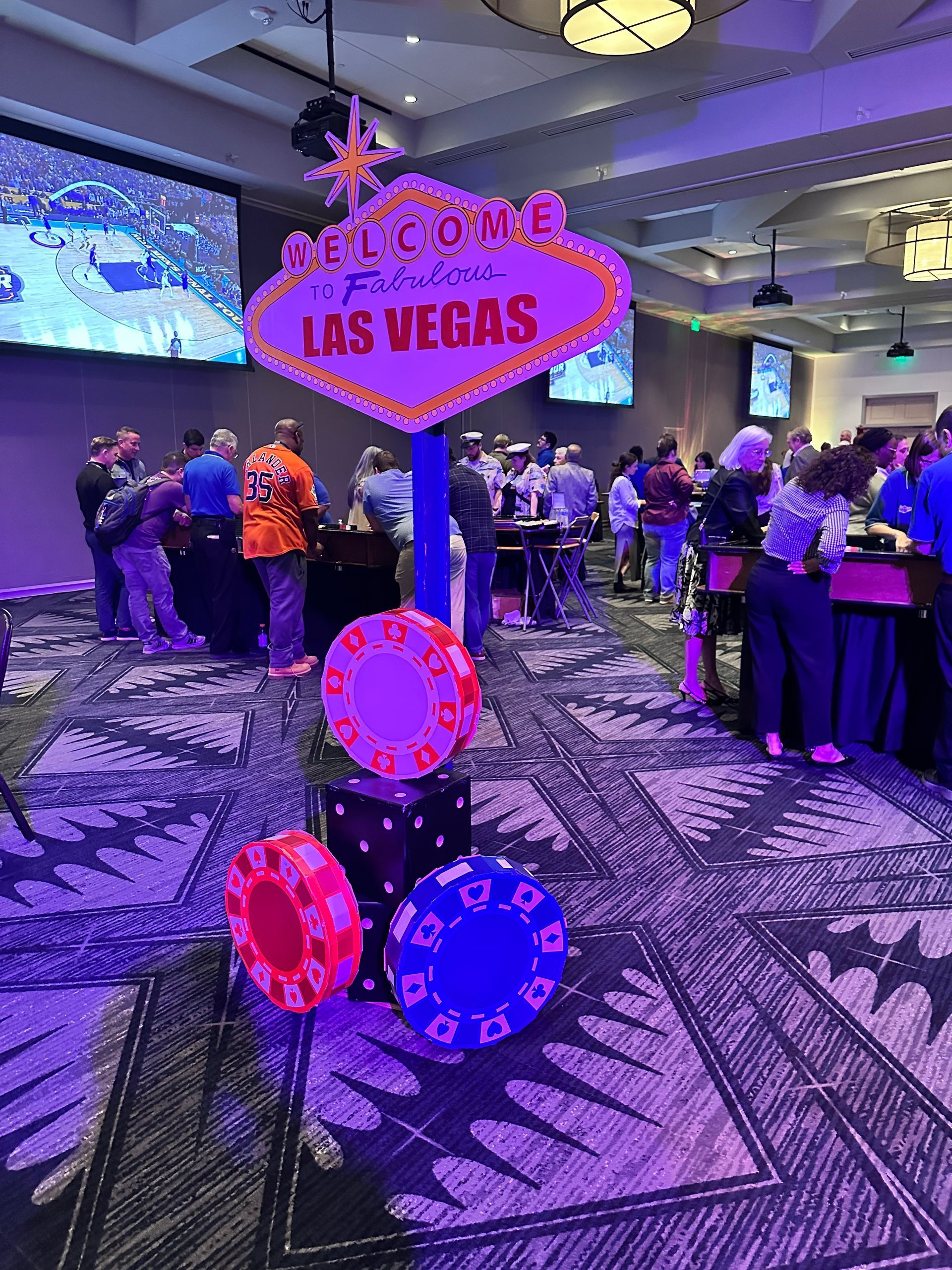 A group of people are standing in a room with a las vegas sign and poker chips.