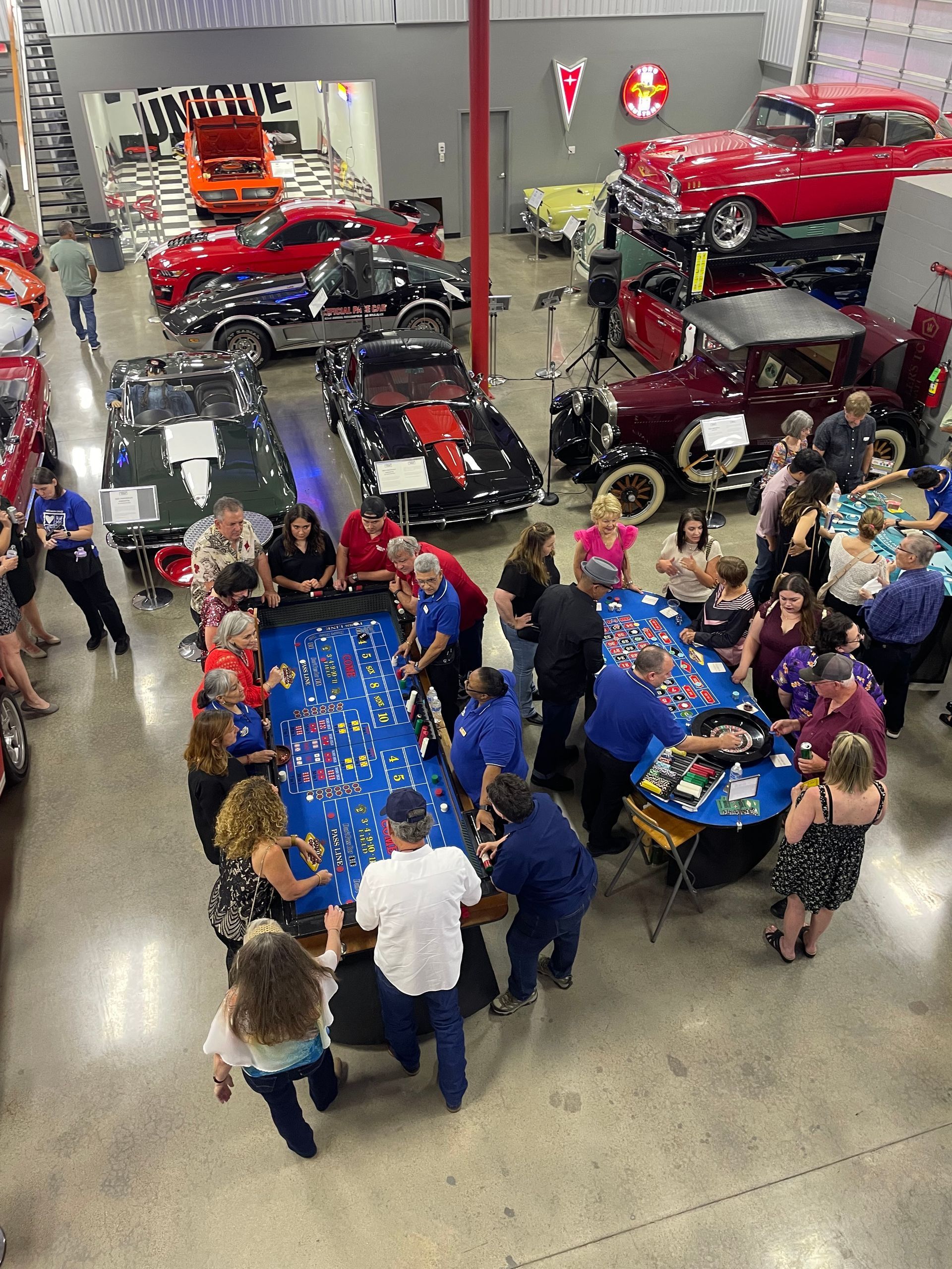 A group of people are gathered around a table in a room filled with cars.