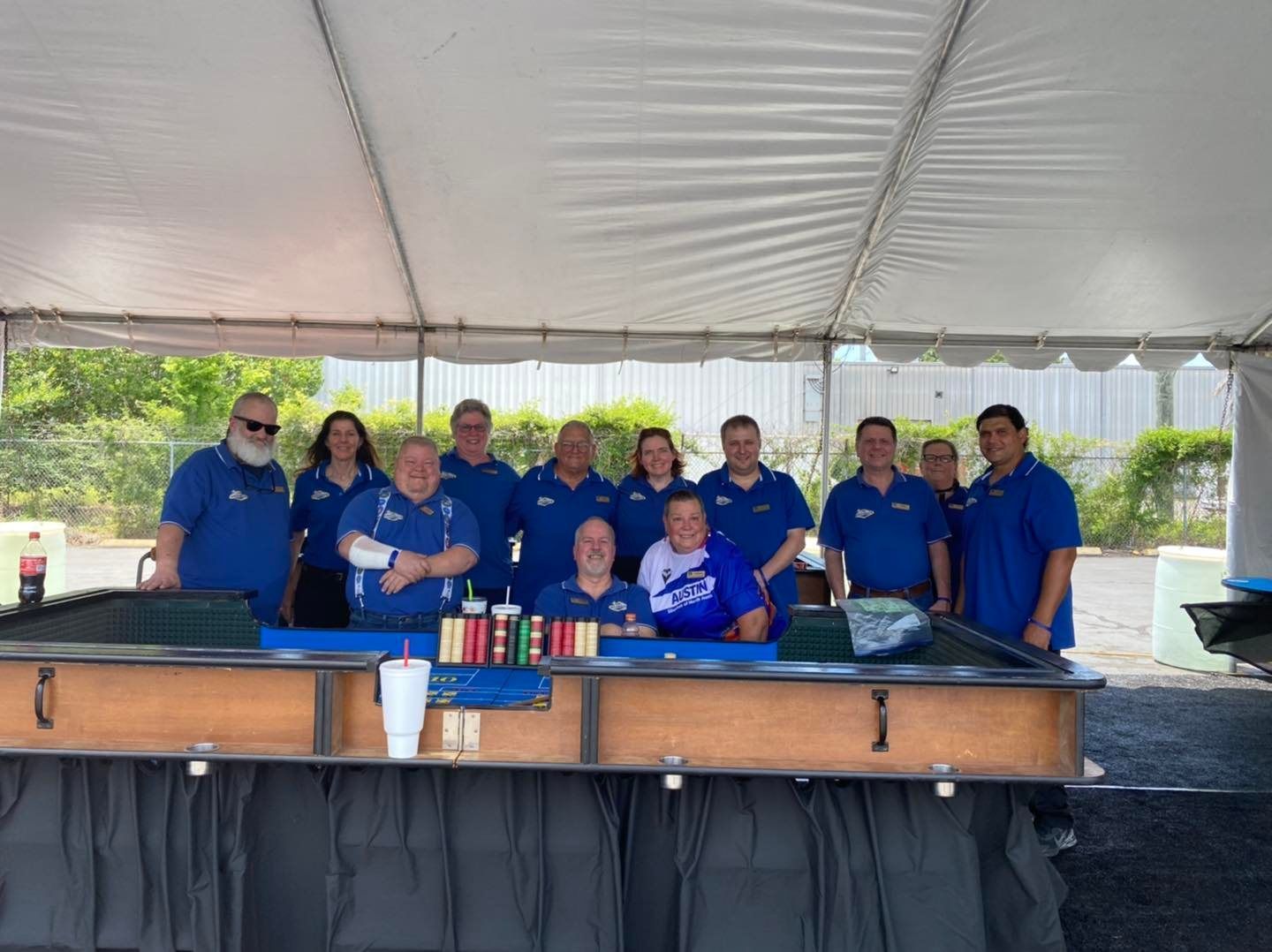 A group of people standing behind a bar under a tent.