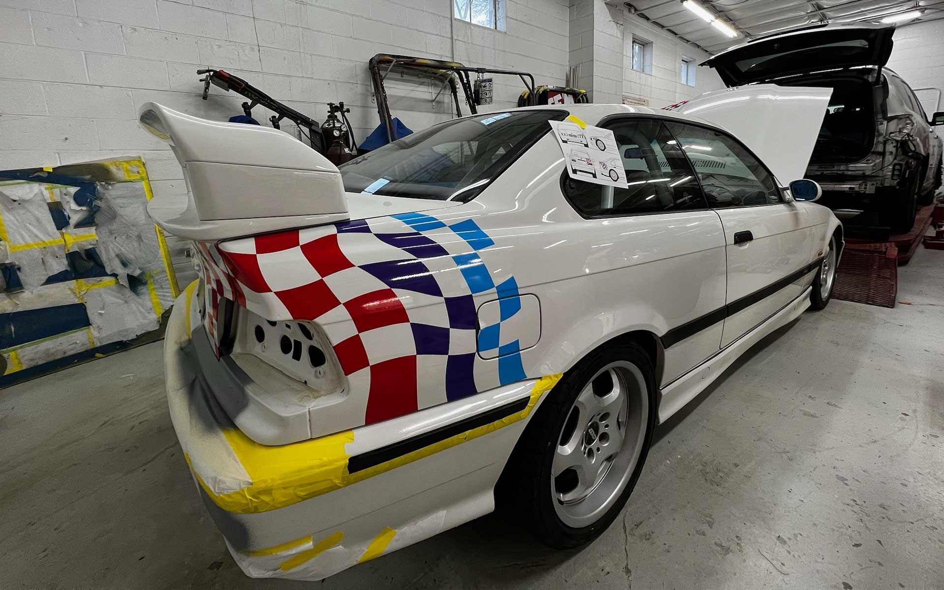 A white car with a checkered stripe on the side is parked in a garage.