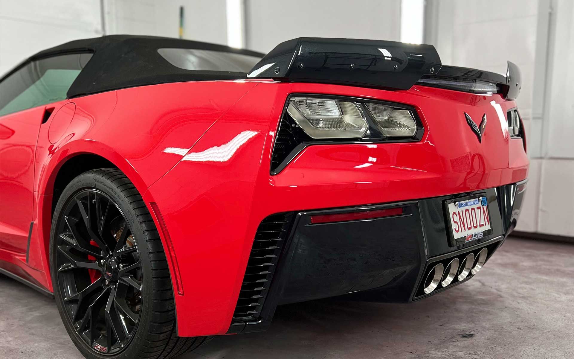 A red corvette convertible is parked in a garage.